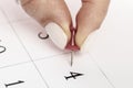 Beautiful female Hand with manicure pushes a red pin on a calendar 4 day Royalty Free Stock Photo