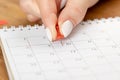 Beautiful female Hand with manicure pushes a red pin on a calendar 10 day Royalty Free Stock Photo