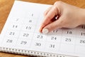 Beautiful female Hand with manicure pushes a red pin on a calendar 23 day Royalty Free Stock Photo