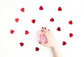 Beautiful female hand with trendy red manicure holding stylish bottle of perfume with spray of vibrant red heart-shaped