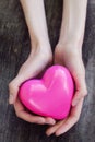 Beautiful female hands holding pink plastic heart