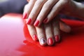 Beautiful female hands with manicure. Bright red nail polish on the red surface. Royalty Free Stock Photo