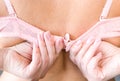 Beautiful female hands with a manicure unfasten the bra.