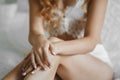 Beautiful female hands with ring on the naked legs - wedding preparation