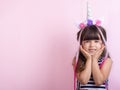 Beautiful female kid in hair hoop with unicorn horn and fashion clothes