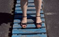 Beautiful female legs in black sandals. Woman's legs wearing sandals. Blue wooden boards. Royalty Free Stock Photo