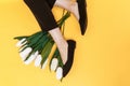 Beautiful female legs are dressed in stylish black flat shoes. black sandals on a yellow background Royalty Free Stock Photo