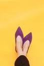 Beautiful female legs are dressed in stylish violet flat shoes. violet sandals on a yellow background Royalty Free Stock Photo