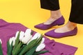 Beautiful female legs are dressed in stylish violet flat shoes. violet sandals on a yellow background Royalty Free Stock Photo