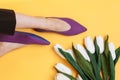 Beautiful female legs are dressed in stylish violet flat shoes. violet sandals on a yellow background Royalty Free Stock Photo