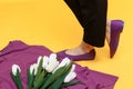 Beautiful female legs are dressed in stylish violet flat shoes. violet sandals on a yellow background Royalty Free Stock Photo