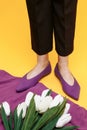 Beautiful female legs are dressed in stylish violet flat shoes. violet sandals on a yellow background Royalty Free Stock Photo