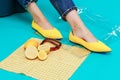 Beautiful female legs are dressed in stylish yellow shoes without a heel. Light yellow summer sandals on a blue background against Royalty Free Stock Photo