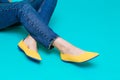 Beautiful female legs are dressed in stylish yellow shoes without a heel. Light yellow summer sandals on a blue background Royalty Free Stock Photo