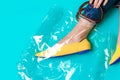 Beautiful female legs are dressed in stylish yellow shoes without a heel. Light yellow summer sandals on a blue background and a Royalty Free Stock Photo