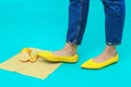 Beautiful female legs are dressed in stylish yellow shoes without a heel. Light yellow summer sandals on a blue background against Royalty Free Stock Photo