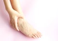 Beautiful female legs and feet Her hands catch ankle pain on a pink background .Concept beauty and medical