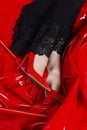 Beautiful female legs in red shoes and black dress with lace on the background of latex red fabric. Conceptual, advertising and Royalty Free Stock Photo