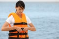 Beautiful female lifeguard putting on life vest near sea Royalty Free Stock Photo