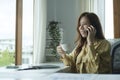 Beautiful female manager holding coffee cup and talking in mobile phone while sitting in modern office Royalty Free Stock Photo