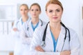 Beautiful female medical doctor standing at hospital in front of medical group. Physician is ready to help patients