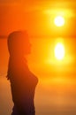 Beautiful female model enjoying sunset at seaside. Calm water of salt lake Elton reflects woman`s silhouette. Sun goes behind Royalty Free Stock Photo