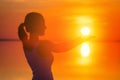 Beautiful female model enjoying sunset and touch sun at seaside. Calm water of salt lake Elton reflects woman`s silhouette. Girl Royalty Free Stock Photo