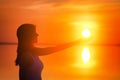 Beautiful female model enjoying sunset and touch sun at seaside. Calm water of salt lake Elton reflects woman`s silhouette. Girl Royalty Free Stock Photo