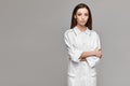 Beautiful female model in medical uniform posing at grey background. Young woman in medical coat, copy space for your