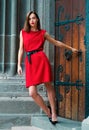 Beautiful female model in summer city in Europe. Trendy woman posing on the street background. Brunette with red dress. Royalty Free Stock Photo