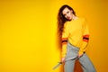 Beautiful female model wears casual comfrotable sweater, poses against yellow background. Copyspace Royalty Free Stock Photo