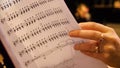 Beautiful female music composer looking at music notes. Woman looks at notes on piano closeup