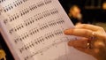 Beautiful female music composer looking at music notes. Woman looks at notes on piano closeup