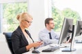 Beautiful female office worker in formalwear with colleague on background Royalty Free Stock Photo