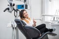 Beautiful female patient with perfect white teeth sitting in dental chair, smiling and showing thumbs up after treatment Royalty Free Stock Photo