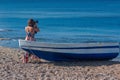 Beautiful female photographer in the dress with professional camera near boat on the sand Royalty Free Stock Photo