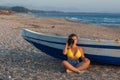 Beautiful female photographer in the bikini with professional camera near boat on the sand Royalty Free Stock Photo