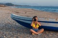 Beautiful female photographer in the bikini with professional camera near boat on the sand Royalty Free Stock Photo