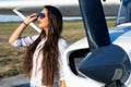 Female pilot in sunglasses with modern small aircraft in background