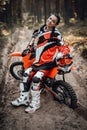 Beautiful female racer wearing protective motocross outfit smiling and looking on the camera while sitting on her bike Royalty Free Stock Photo