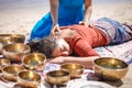 Beautiful female receiving energy sound massage with singing bowls and body massage on a river bank Royalty Free Stock Photo