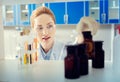 Beautiful female scientist taking bottle with chemical liquid