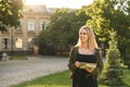 Beautiful female student with broad smile holding notebooks and looking aside in the college garden. Smiling attractive cute Royalty Free Stock Photo