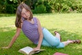 Beautiful female teenage reading a book on the grass