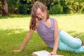 Beautiful female teenage reading a book on the grass