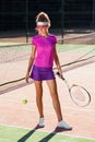 Beautiful female tennis player hitts the tennis ball to the ground using a racket while walking on the outdoor court. Royalty Free Stock Photo