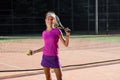 Beautiful female tennis player hitts the tennis ball to the ground using a racket while walking on the outdoor court. Royalty Free Stock Photo