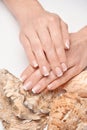 Beautiful Female well-groomed Hands with French manicure holding sea shell over light background Royalty Free Stock Photo