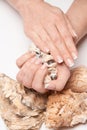 Beautiful Female well-groomed Hands with French manicure holding sea shell over light background Royalty Free Stock Photo