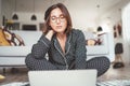 Beautiful female writer dressed pajamas typing notebook keyboard writing novel sitting cross-legged on living room floor with